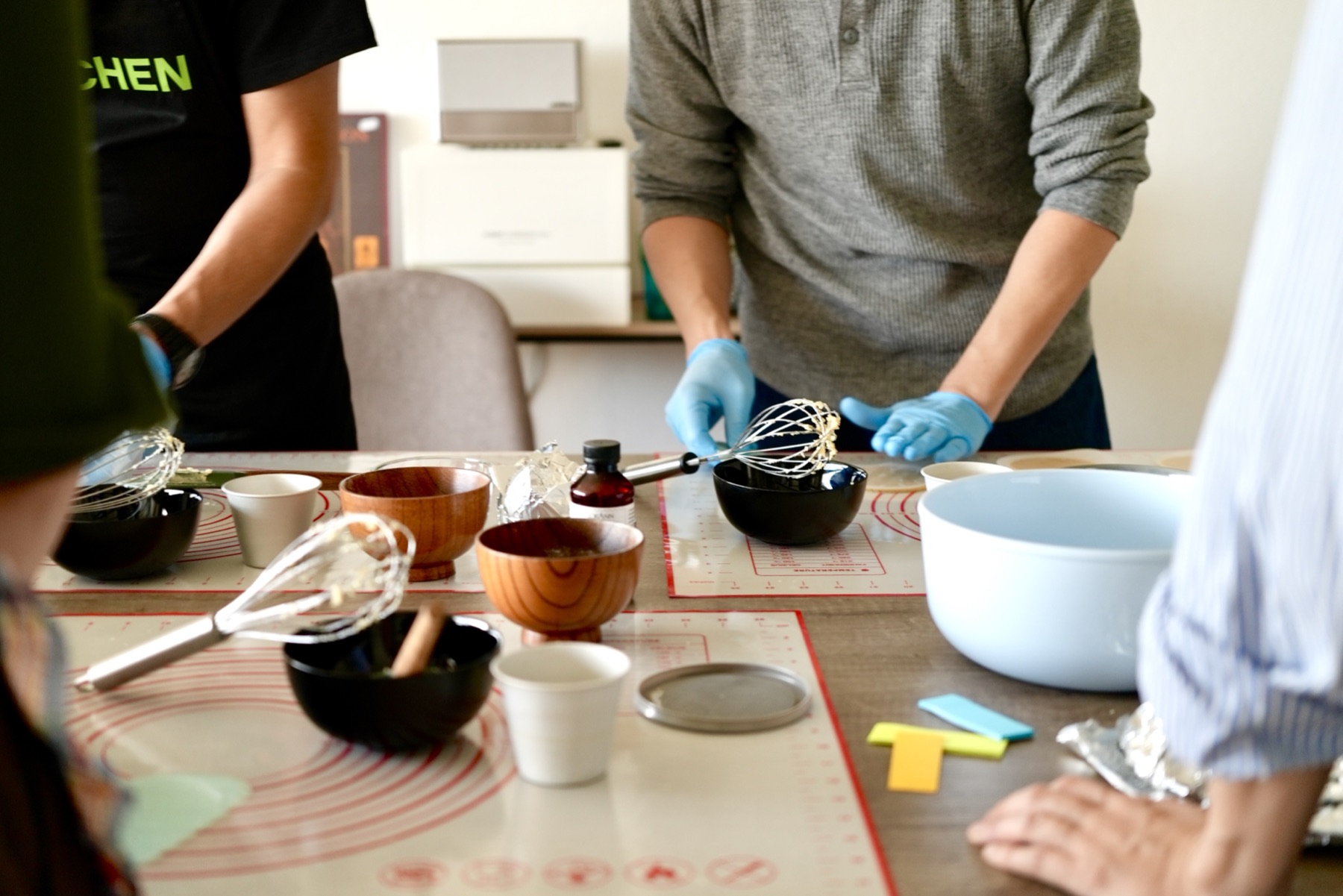 Participantes del taller en una mesa con varillas, boles y bases de silicona para hornear.