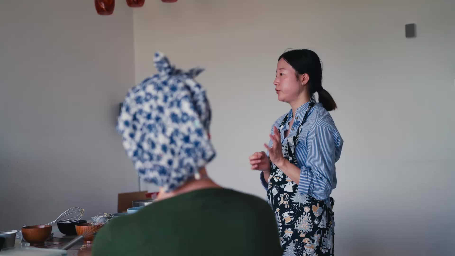 Risa hablando al grupo en la cocina.