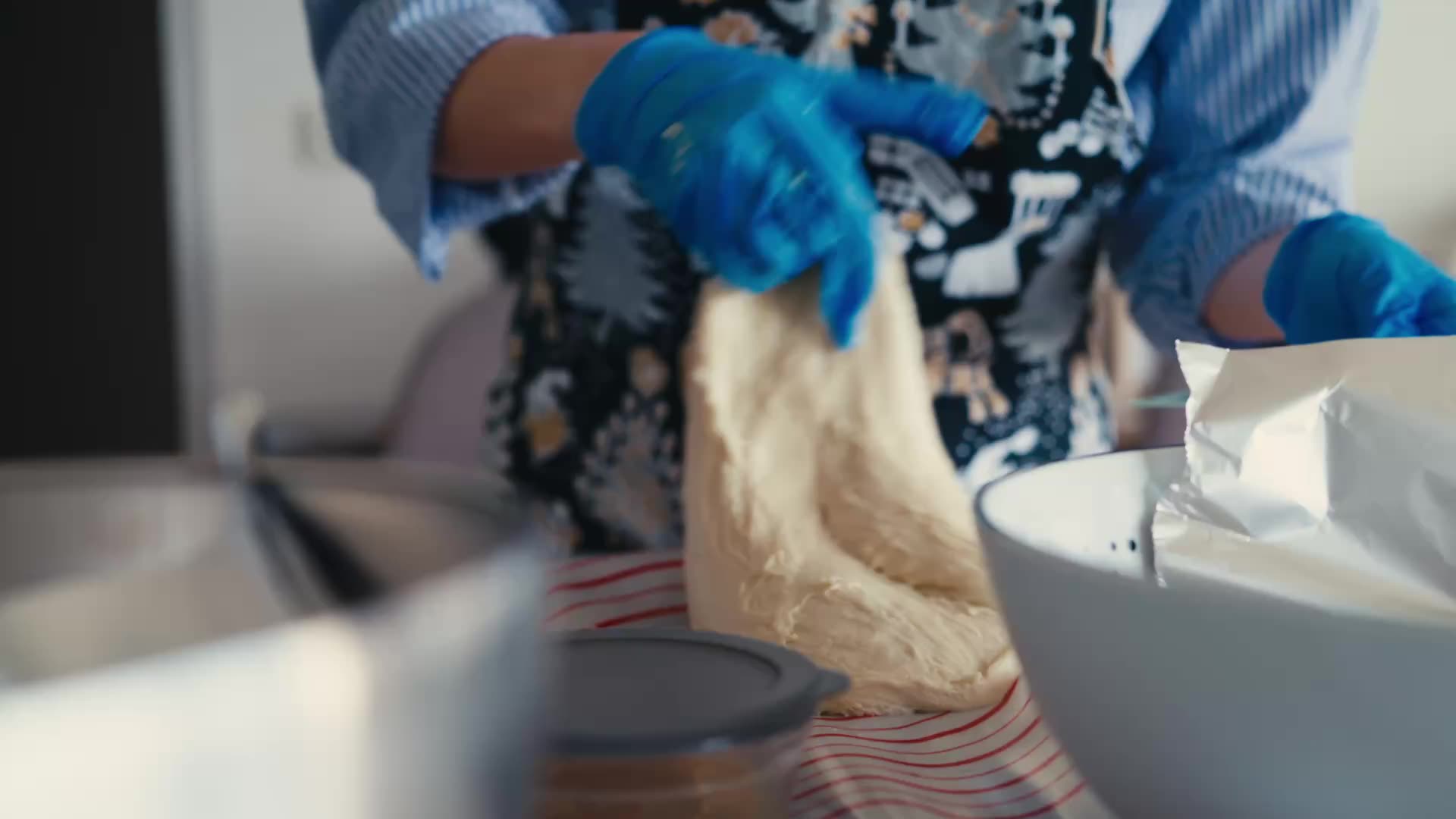 Manos con guantes levantando un trozo de masa blanda.